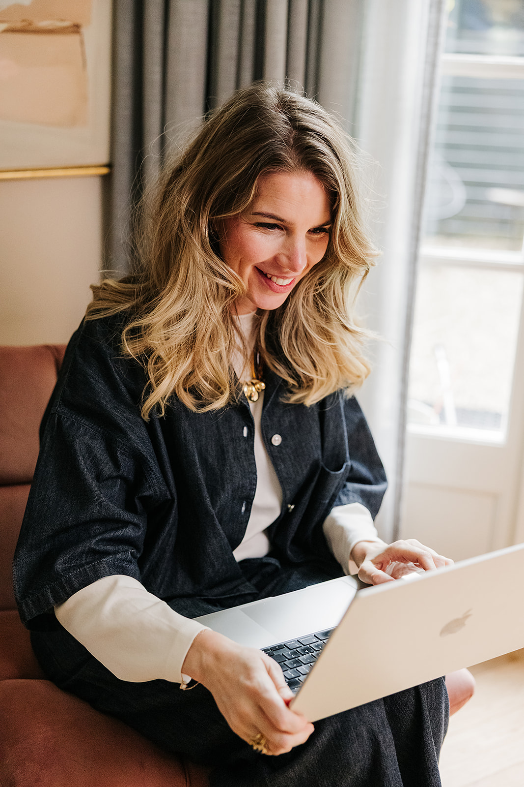 Charlotte lachend achter haar laptop, thuis